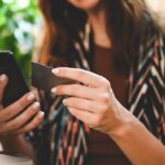 close up of brunette lady tapping an NFC business card on a mobile phone
